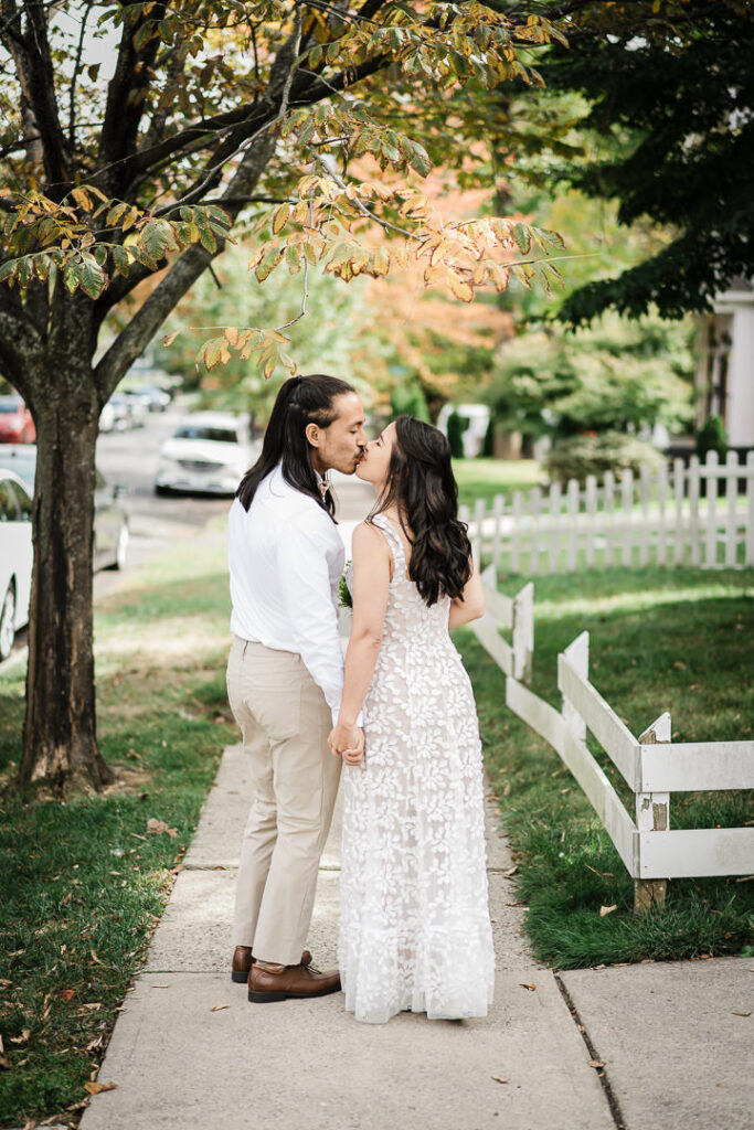 Romantic moment of couple kissing under fall foliage after backyard wedding in NJ