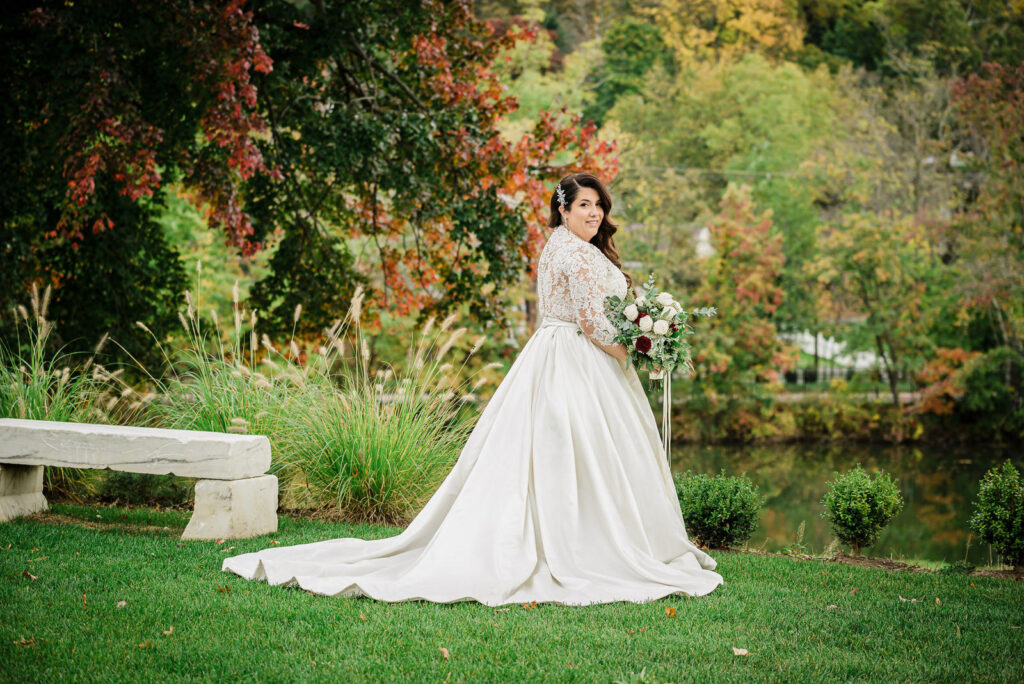 Bride showcasing ball gown train with fall foliage at Ramsey Country Club by Alex Kaplan