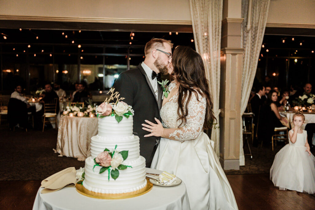 Newlyweds kissing after cutting cake Ramsey Country Club fall wedding by Alex Kaplan Photography