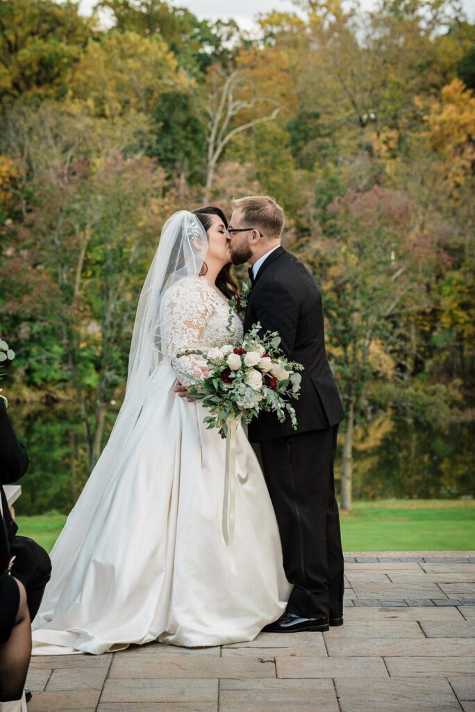 First kiss as married couple with autumn foliage Ramsey Country Club by Alex Kaplan