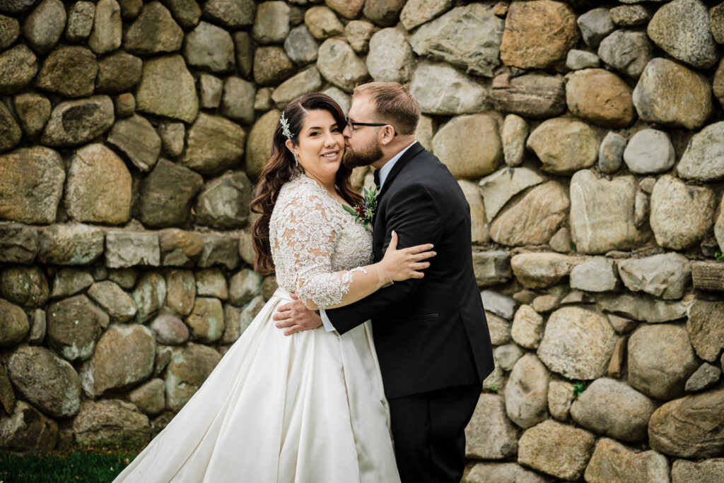 Close-up of newlyweds kissing by stone wall at Ramsey Country Club Alex Kaplan Photography