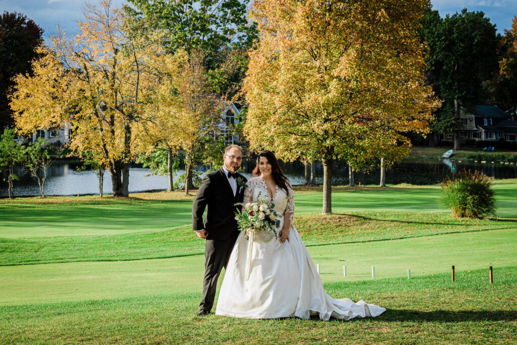 Bride and groom with full view of Lakeside Grille stone building Ramsey Country Club by Alex Kaplan