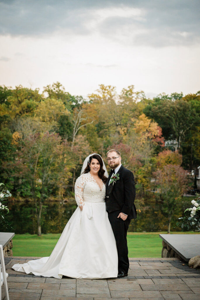 Couple at ceremony site with stone bench and fall foliage Ramsey Country Club by Alex Kaplan