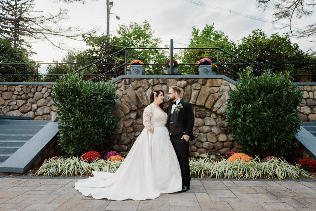 Couple on stone steps with colorful mums Ramsey Country Club fall wedding by Alex Kaplan