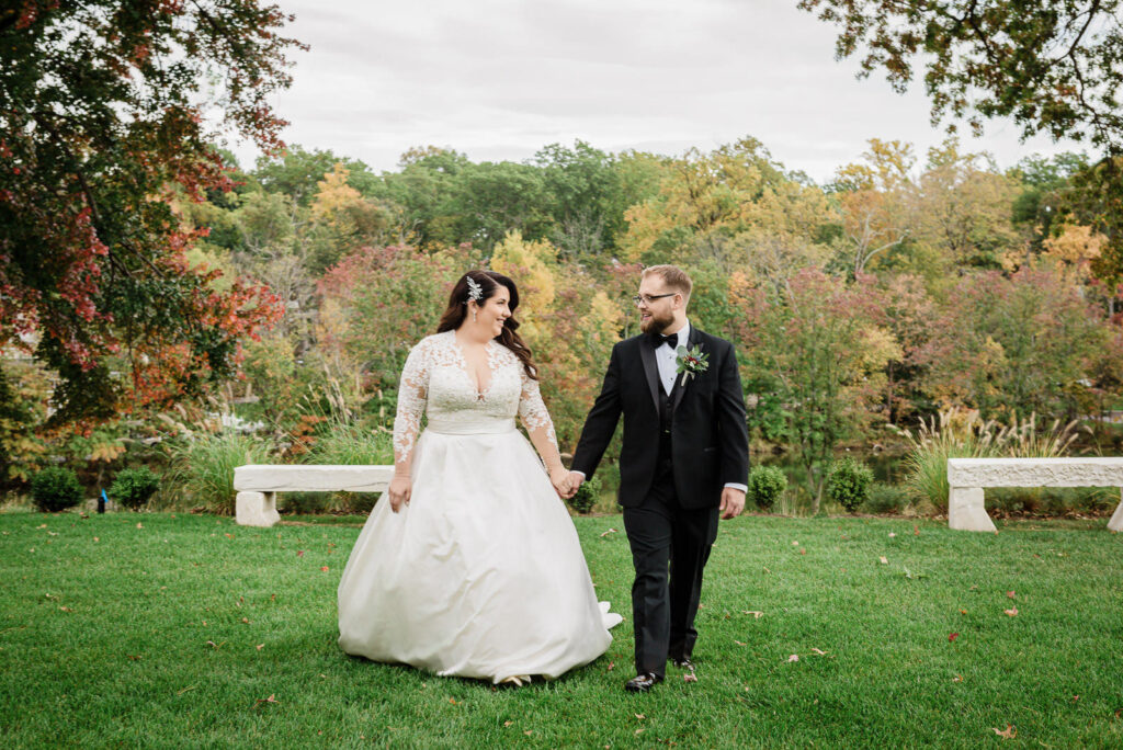 Bride and groom walking on manicured lawn with fall colors Ramsey Country Club by Alex Kaplan