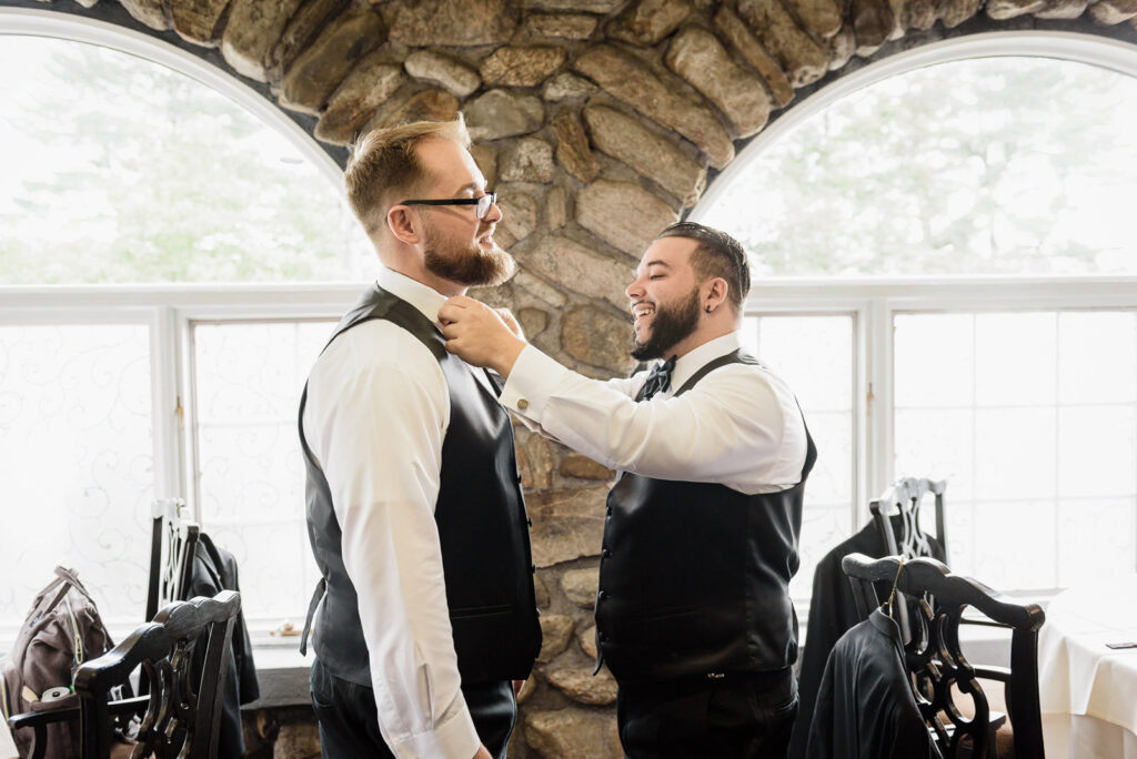 Groom getting bow tie adjusted by groomsman at Ramsey Country Club wedding by Alex Kaplan