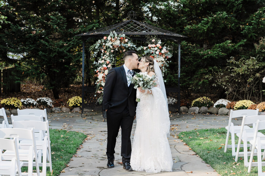 Bride and groom romantic kiss at ceremony gazebo with floral arch at The English Manor Ocean Township wedding