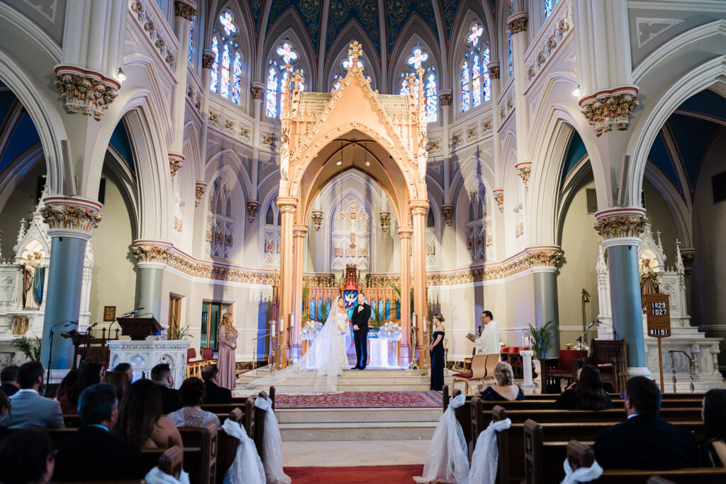 Catholic wedding ceremony at St. Henry's Church Bayonne NJ showing Neo-Gothic architecture ornate altar and stained glass windows by Alex Kaplan Photography
