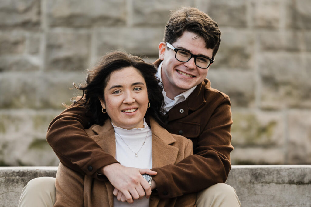 Engaged couple embracing while sitting on stone steps at Verona Park in New Jersey photographed by Alex Kaplan