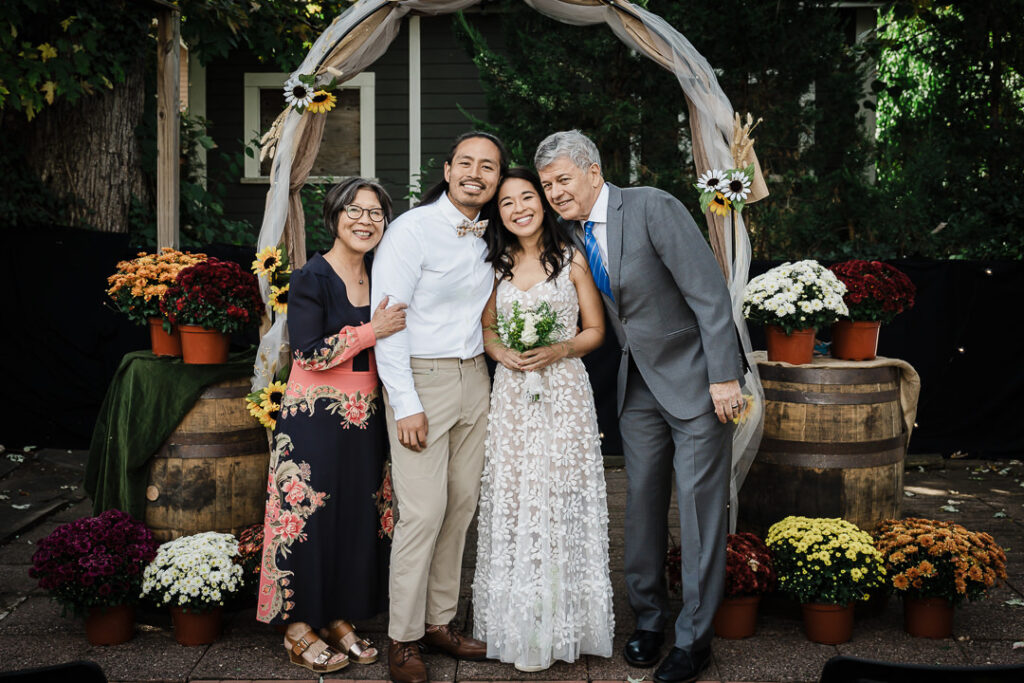 Couple with parents celebrating at rustic fall ceremony arch in NJ backyard