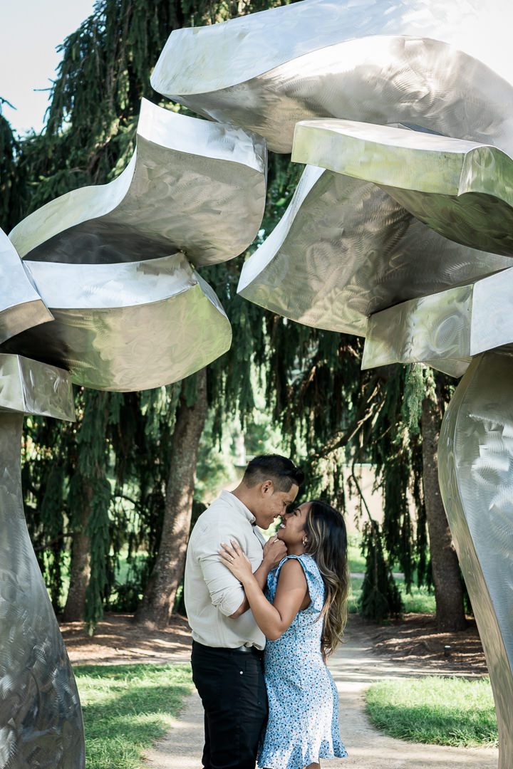 Creative proposal photography at Grounds For Sculpture New Jersey showing couple among artistic sculptures captured by experienced proposal photographer by Alex Kaplan