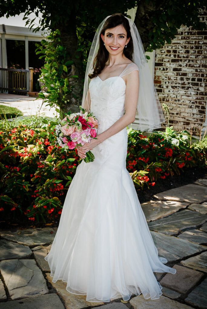 Bride in mermaid wedding gown with cathedral veil in sunlit garden at Hamilton Farm Golf Club