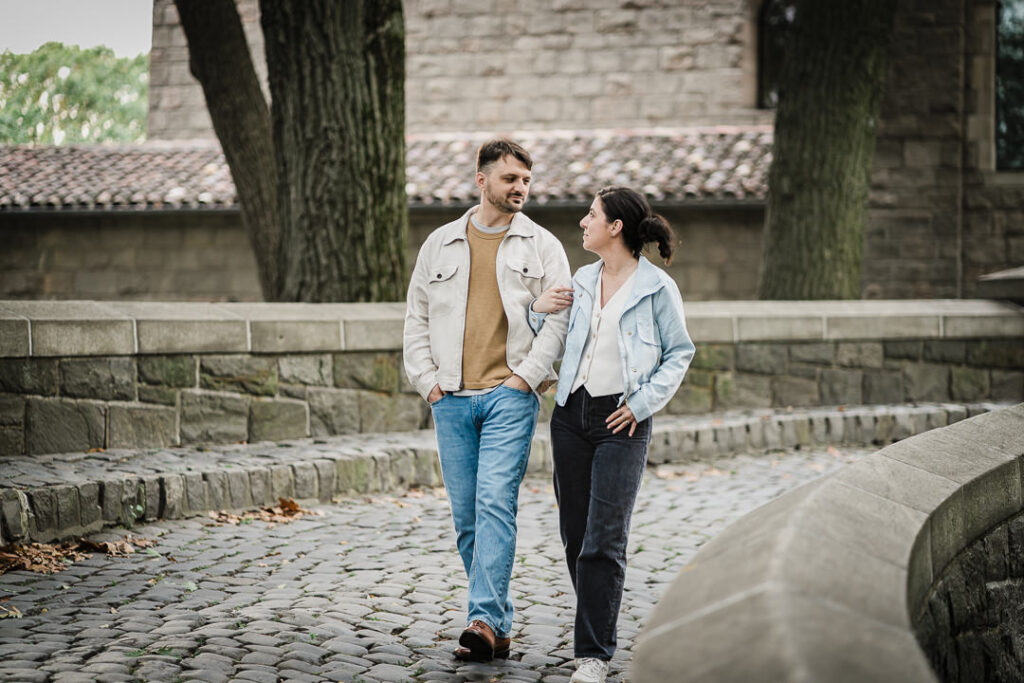 Couple walking together on cobblestone street at Fort Tryon Park engagement session in NYC