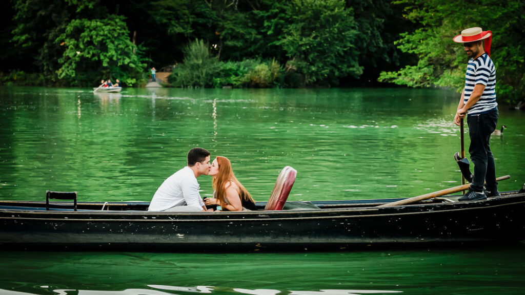 Wide angle view of gondola proposal at Central Park's Loeb Boathouse with gondolier and waterfront restaurant backdrop