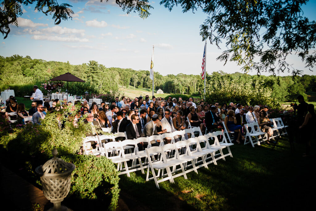 Wedding guests assembled at outdoor ceremony overlooking Hamilton Farm Golf Club's rolling fairways at golden hour