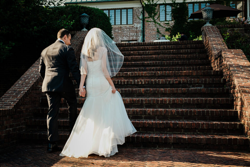 Bride and groom ascending dramatic brick staircase with architectural lighting at Hamilton Farm