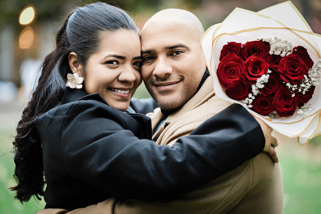 Groom lifts newly engaged bride in celebration with illuminated MARRY ME letters in background, fall garden proposal Van Vleck Montclair NJ
