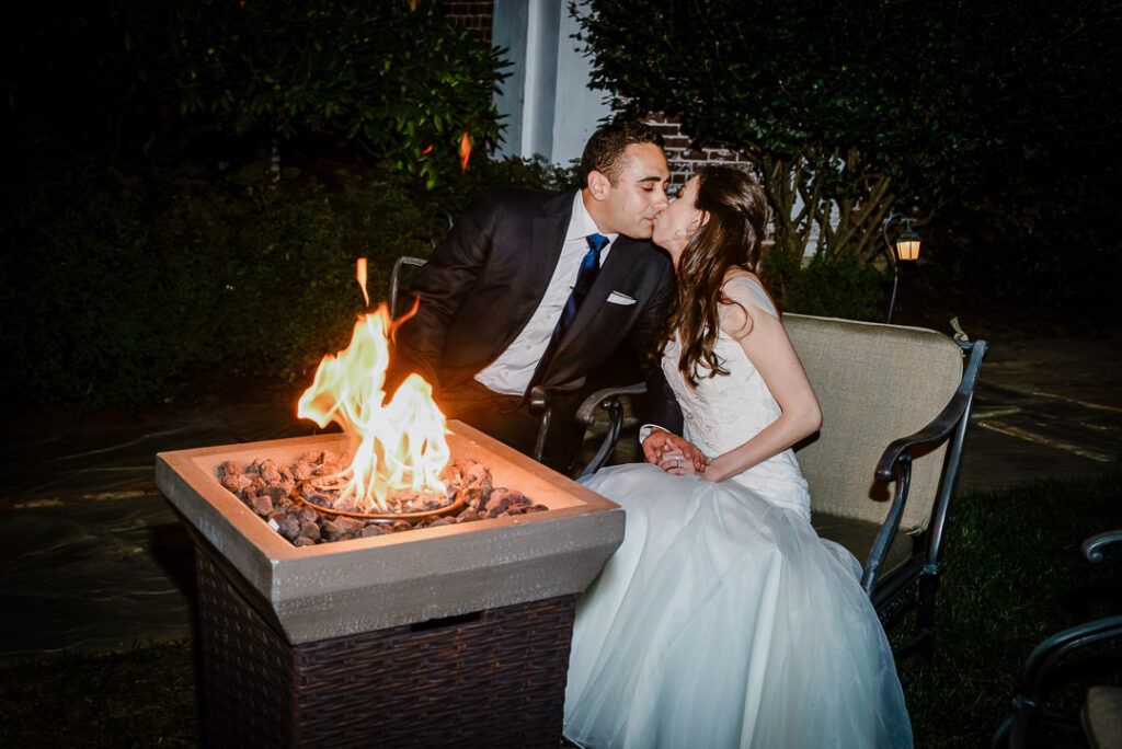 Romantic end-of-night moment with couple kissing by outdoor fire pit under stars at Hamilton Farm