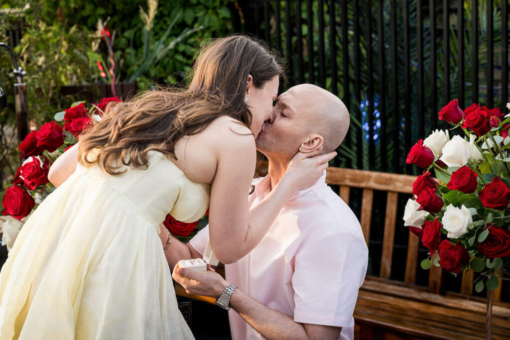 Newly engaged couple shares emotional kiss seconds after she said yes on NYC rooftop surrounded by red and white roses, Northern New Jersey proposal photographer Alex Kaplan