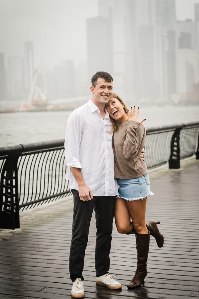 Excited bride-to-be showing off engagement ring with fiance at Pier 13 Hoboken after rainy proposal