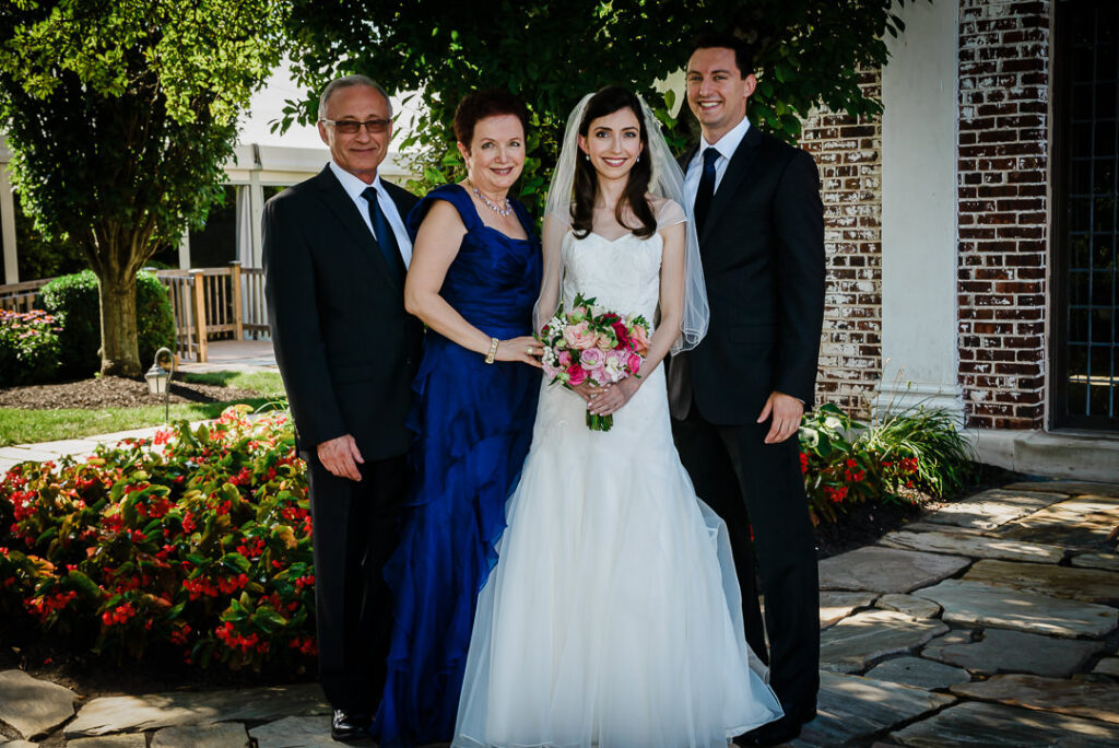 Complete family portrait with bride, groom, and both sets of parents in garden setting