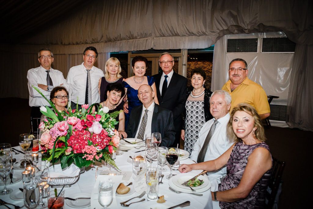 Multi-generational family enjoying dinner together at elegant reception table with pink floral centerpiece