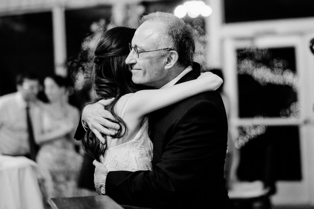 Tender black and white moment of bride dancing with father in emotional father-daughter dance