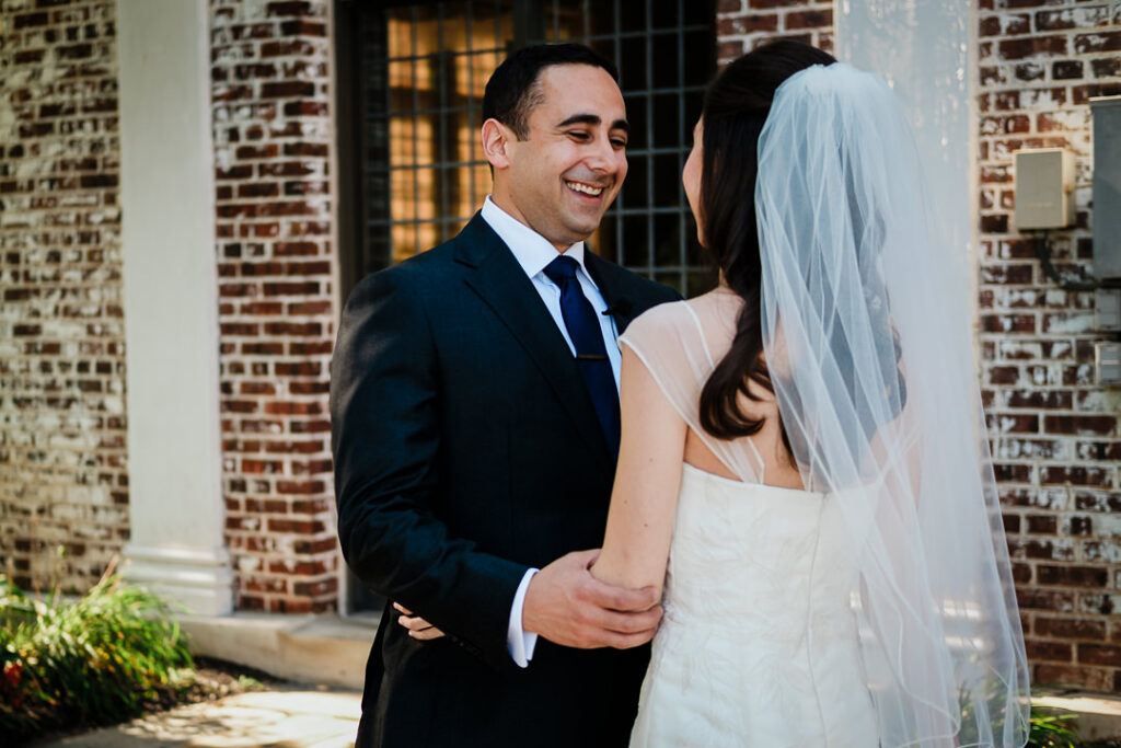 Groom seeing bride for first time against historic brick facade at Hamilton Farm Golf Club Jewish wedding