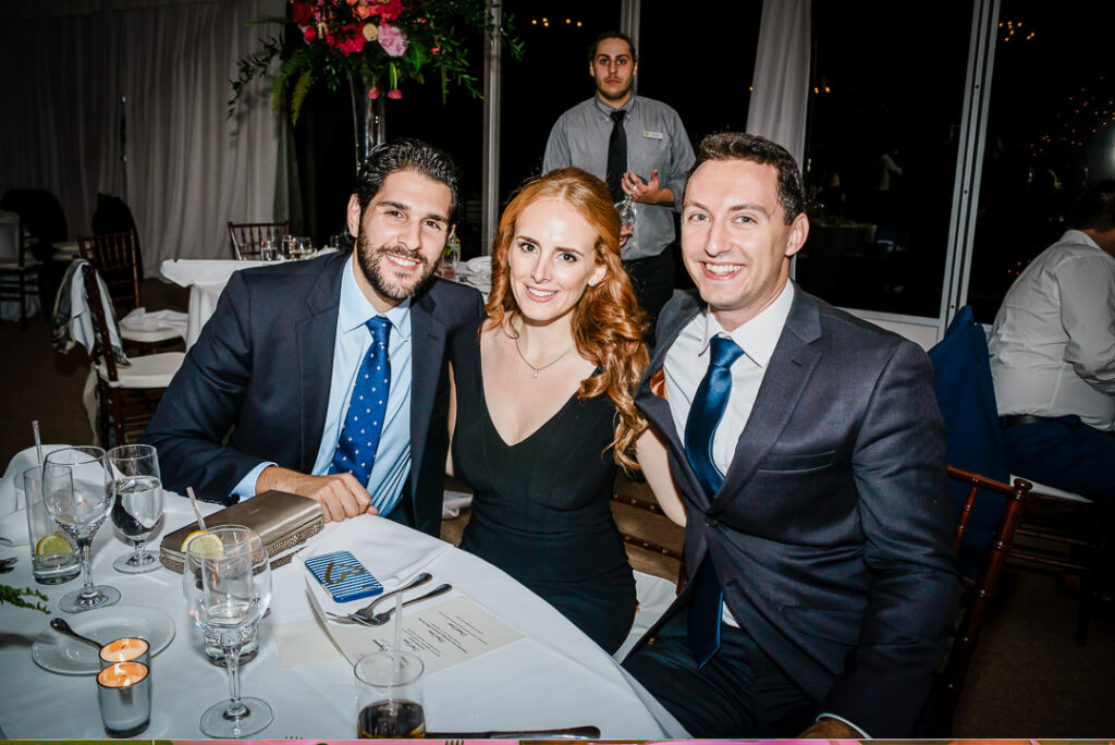 Group of friends smiling together at reception table with white linens and elegant place settings
