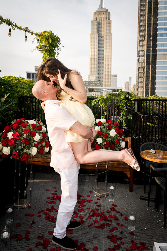 Groom lifts newly engaged bride in celebration on rooftop with Empire State Building and NYC skyline, Alex Kaplan proposal photographer Northern NJ