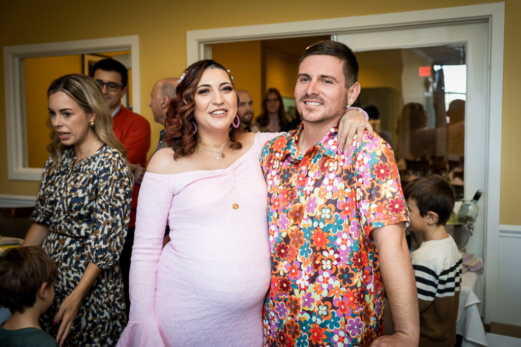 Mom-to-be and partner smiling together at groovy themed baby shower at Delpino Restaurant NJ