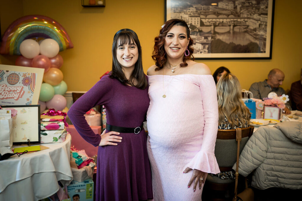 Friends posing with rainbow balloon arch backdrop at Delpino Restaurant baby shower celebration