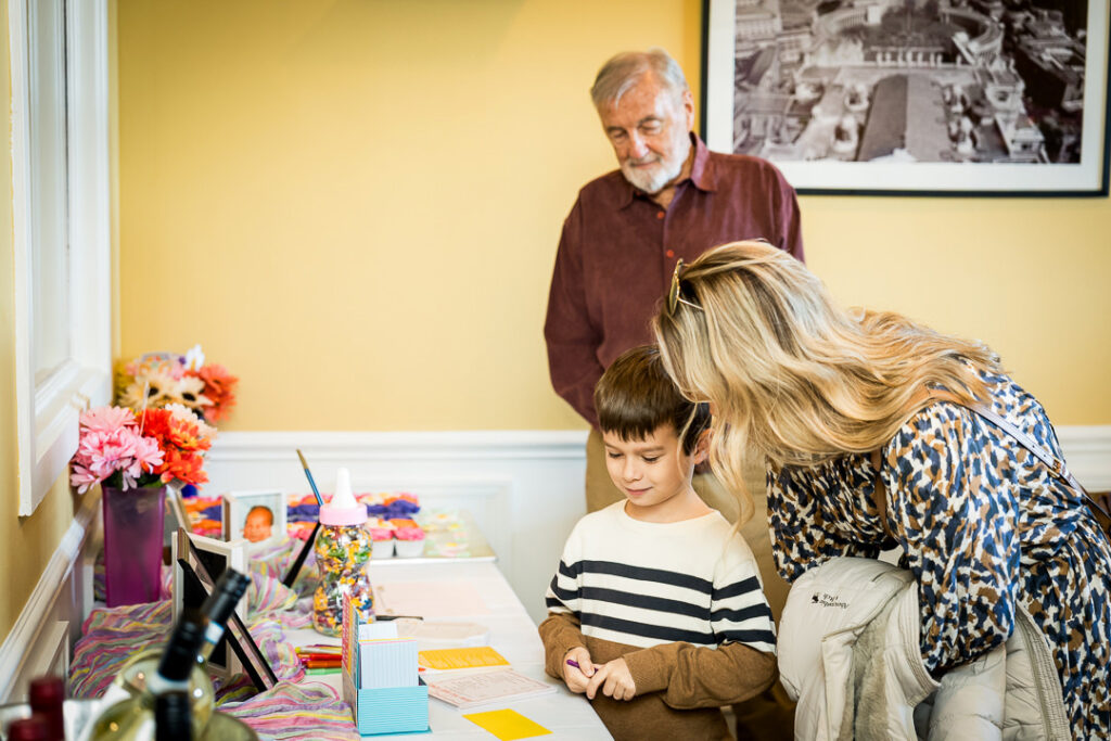 Child with family participating in baby shower guestbook activities at groovy themed celebration NJ
