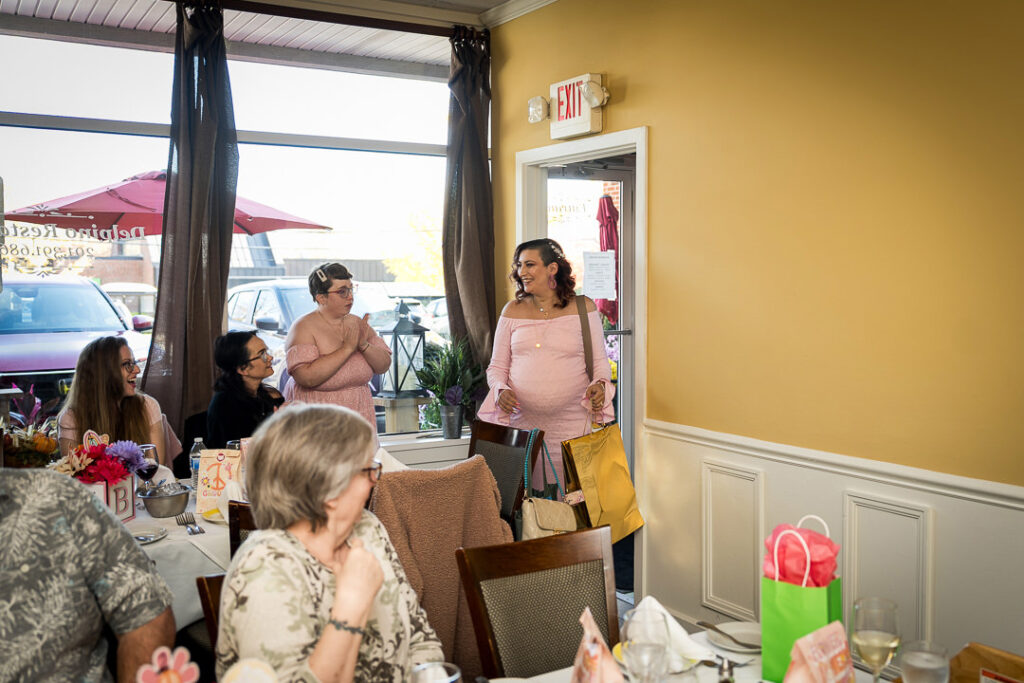 Pregnant mom-to-be standing with guests during groovy baby shower celebration at Delpino NJ
