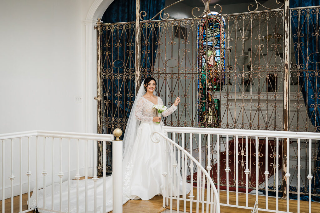 Elegant bride portrait by ornate gate on mansion staircase James Ward Mansion Westfield wedding by Alex Kaplan