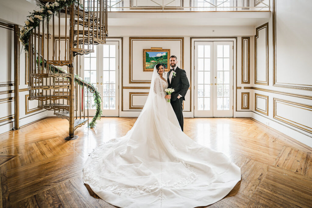 Bride and groom with dramatic cathedral train on spiral staircase James Ward Mansion by Alex Kaplan Photography