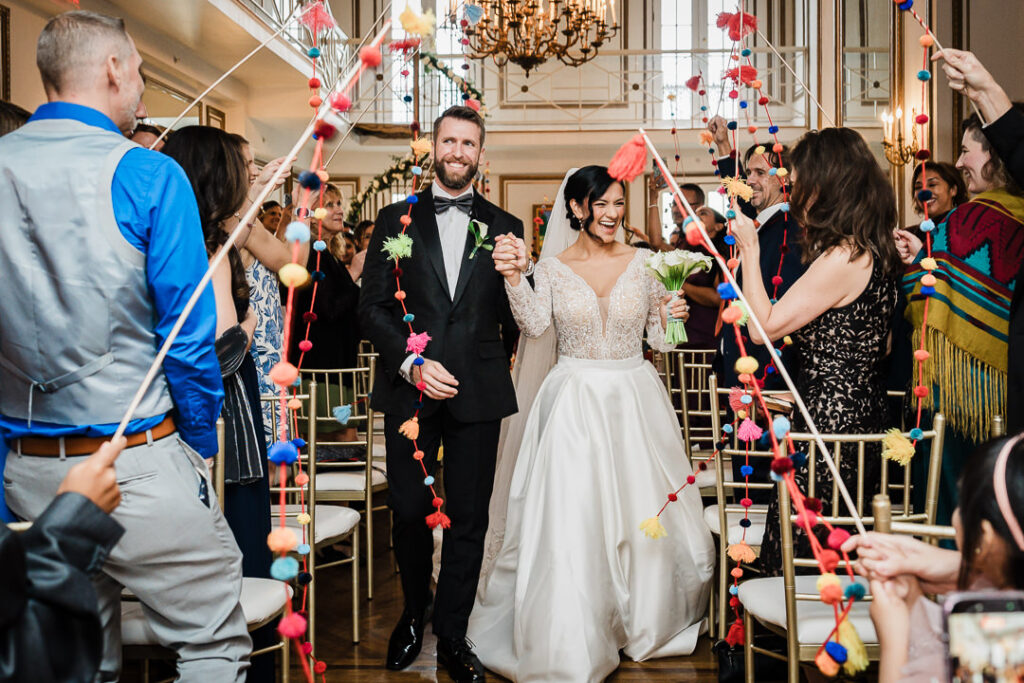 Bride and groom walking through colorful pom-pom ceremony exit James Ward Mansion Westfield by Alex Kaplan Photography