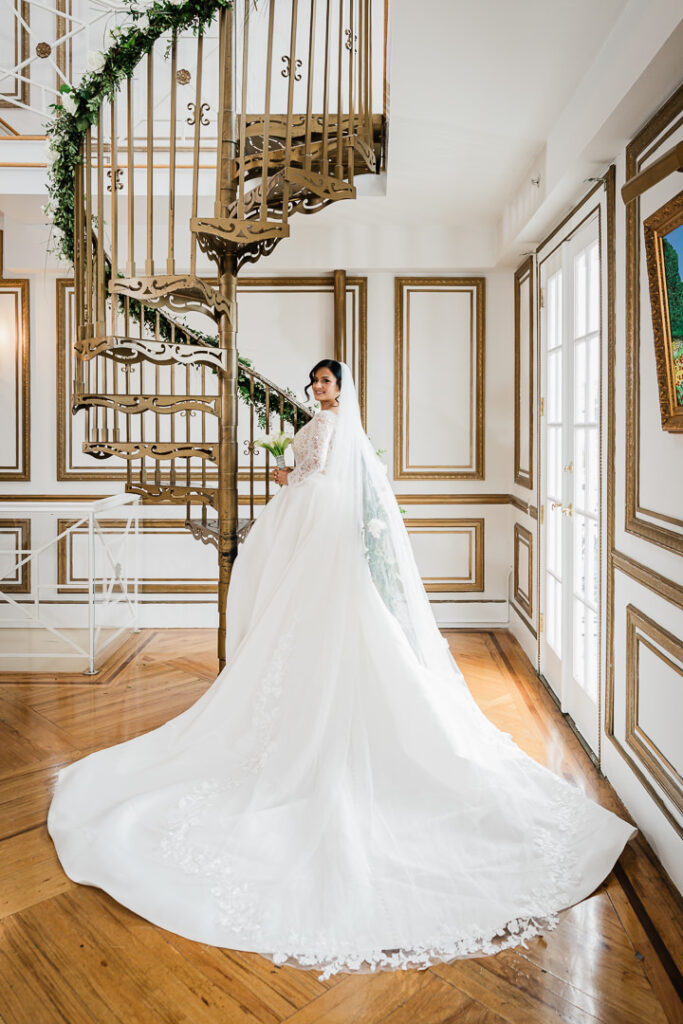 Elegant bridal portrait on ornate spiral staircase with greenery at James Ward Mansion Westfield by Alex Kaplan