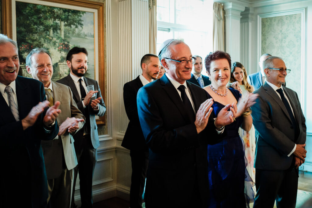 Family and guests applauding during intimate Ketubah signing ceremony at Hamilton Farm Golf Club