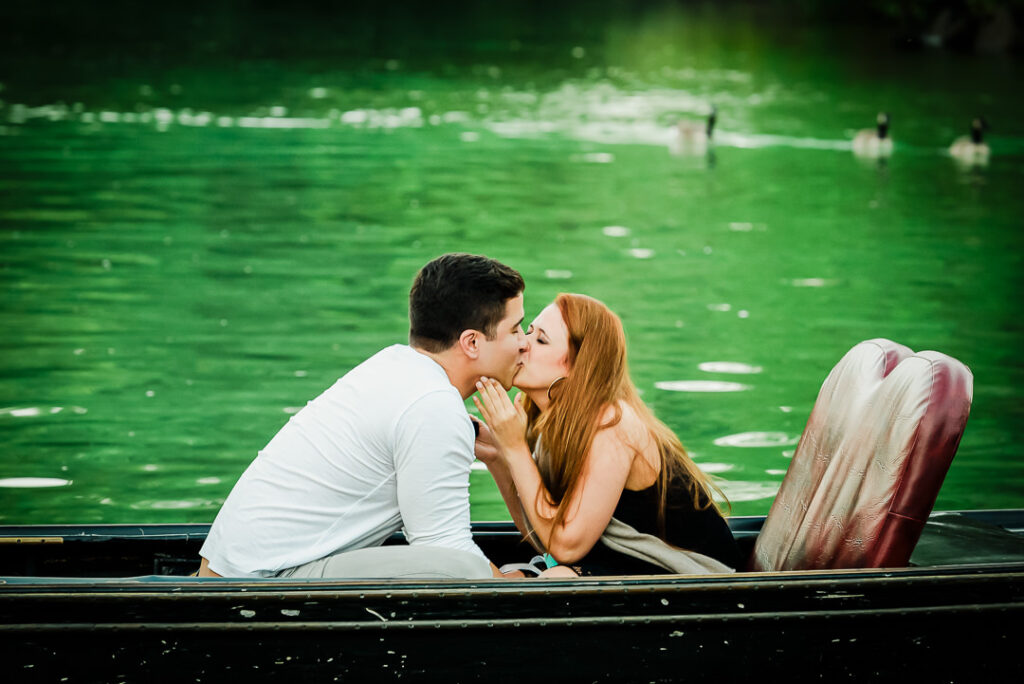 Newly engaged couple sharing first kiss after proposal on Central Park gondola ride at Loeb Boathouse