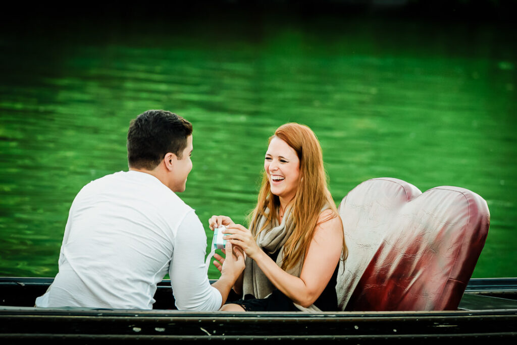 Happy couple toasting with champagne during gondola engagement at Central Park Loeb Boathouse