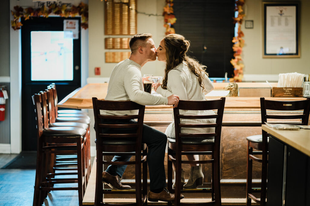 Indoor engagement photography at Morristown members bar with couple kissing with fall decorations