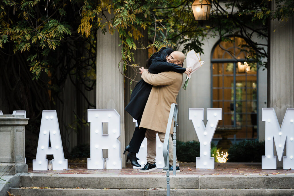 Newly engaged couple embraces with red roses bouquet after Van Vleck Gardens proposal, Northern New Jersey engagement photographer Alex Kaplan