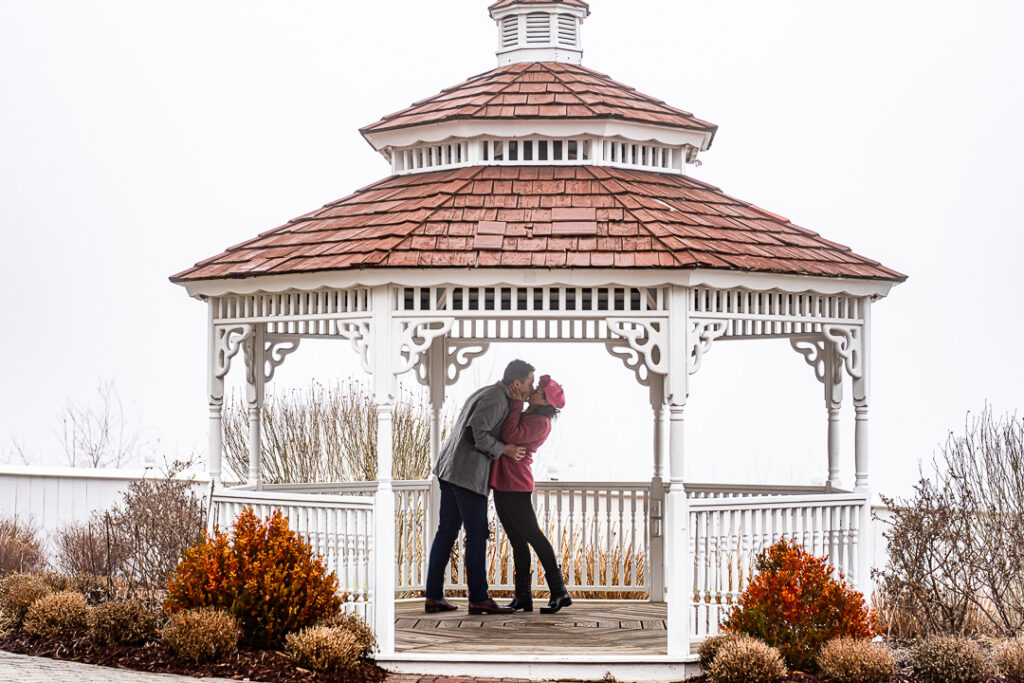 Newly engaged couple shares first kiss beside Victorian gazebo at Mount Fuji in Hillburn.