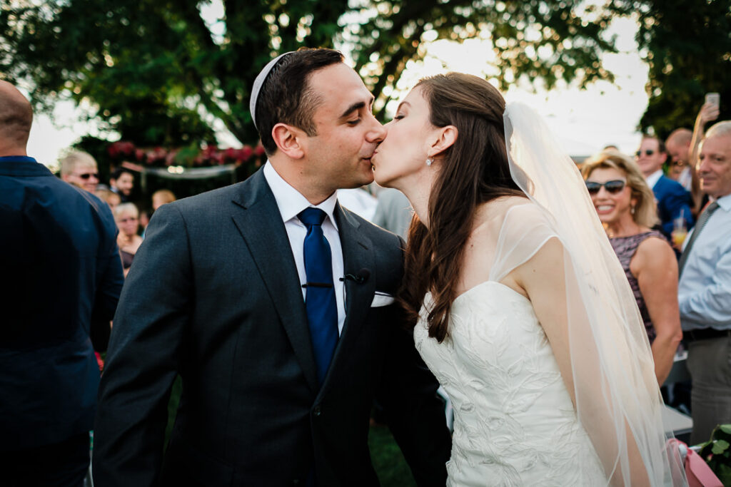 Couple kissing during recessional as wedding guests celebrate with applause at sunset Hamilton Farm ceremony