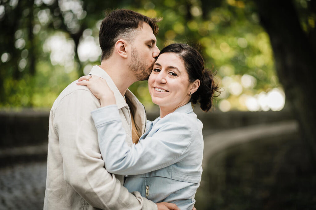 Close-up engagement photo of couple with natural tree bokeh at Fort Tryon Park near The Cloisters