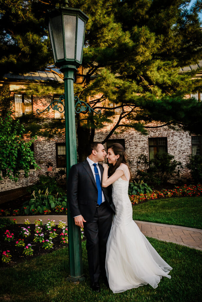 Couple sharing intimate moment by antique green lamppost with dramatic architectural lighting at dusk
