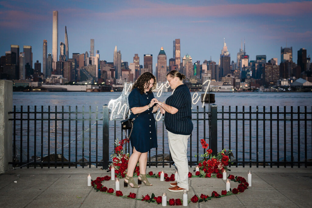 Hoboken waterfront proposal photographer captures romantic setup with NYC skyline views red roses and candles at sunset
