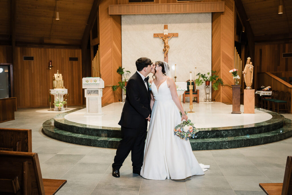 Wide angle portrait of newlyweds at Notre Dame of Mt Carmel Church showing A-frame architecture