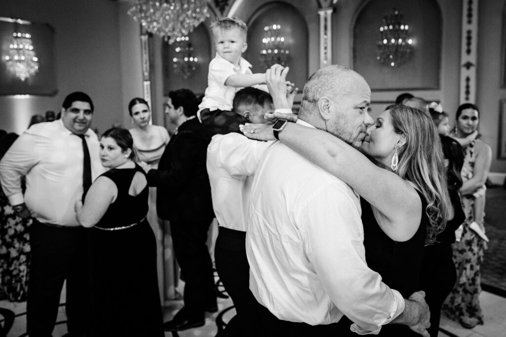 Guest dancing with baby on shoulders during reception at Lucien's Manor captured by documentary photographer Alex Kaplan